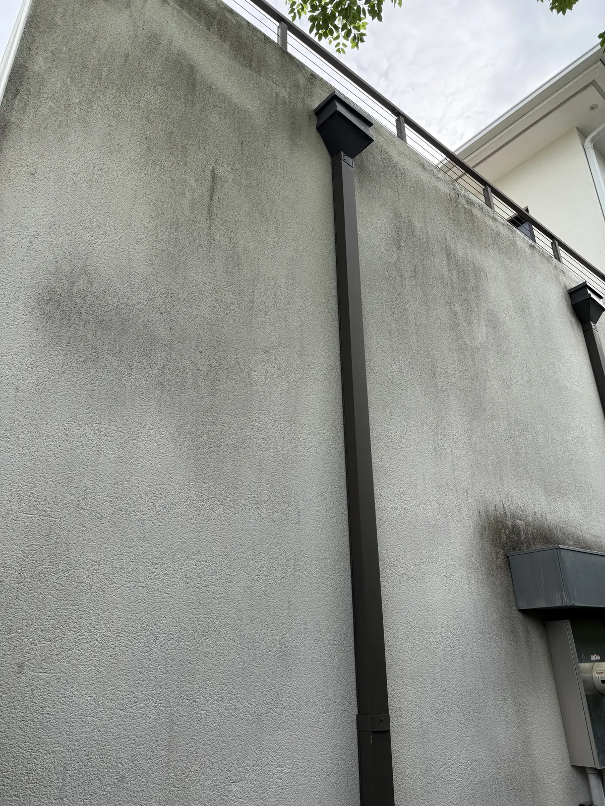 Two-story stucco wall with organic streaking before soft washing
